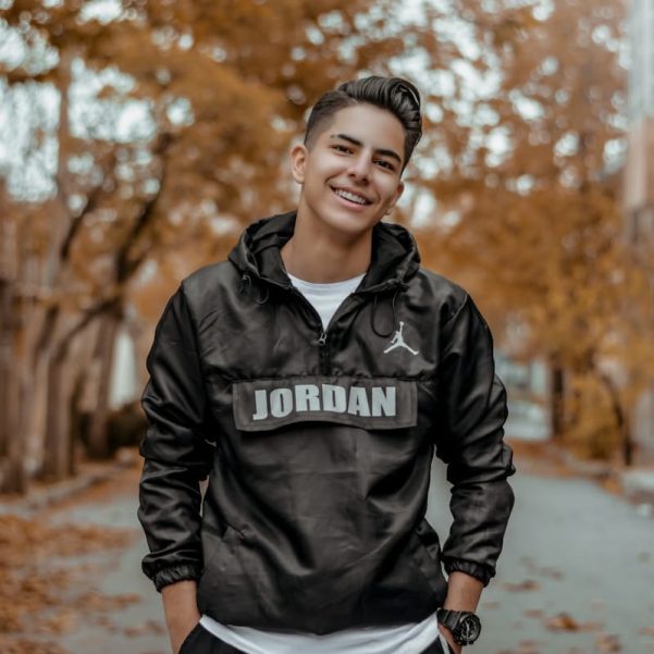 man in black leather jacket standing on road during daytime