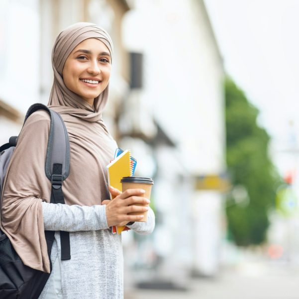 Muslim girl student drinking coffee on street before studying