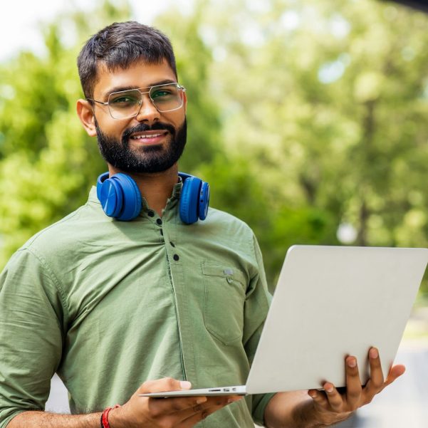 Portrait Indian student programmer using laptop computer in park