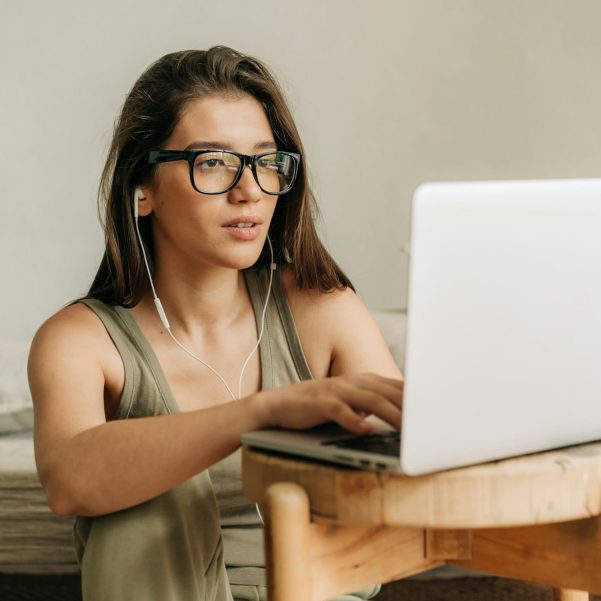 Young female student studying using laptop and headphones.